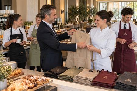 Remise de tabliers personnalisés au personnel d’un hôtel avec un symbole assorti.